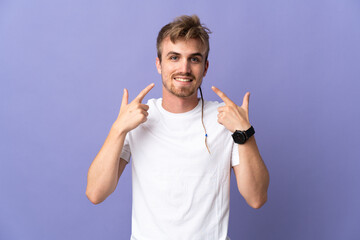 Young handsome blonde man isolated on purple background giving a thumbs up gesture