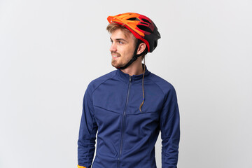 Young cyclist blonde man isolated on white background looking to the side and smiling