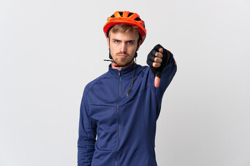 Young cyclist blonde man isolated on white background showing thumb down with negative expression