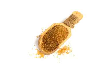 Close up one wooden scoop spoon full of raw brown sugar with pinch spilled and spread around, isolated on white background, elevated top view, directly above. Sprinkled with brown sugar. Cane sugar. 