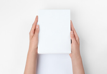 Woman holding book with blank cover on white background, closeup. Space for design