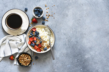 Breakfast - cottage cheese with berries and a cup of coffee, top view. Granola with nuts, honey and strawberries.