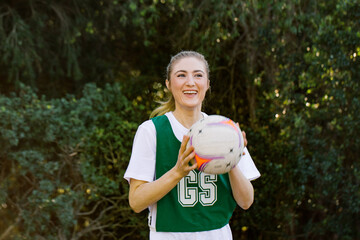 horizontal shot of a young smiling woman in sports wear holding a net ball with two hands