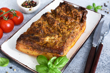 Pork pork baked with garlic and spices on a plate on a dark background.
