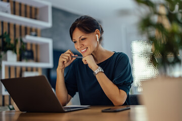 Smiling businesswoman looking at laptop. Working overtime.