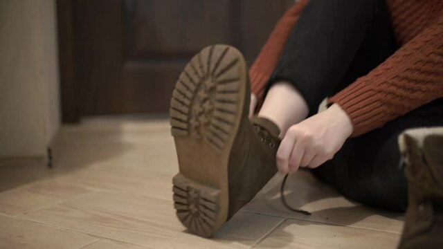 The girl puts on winter shoes indoors. She puts on a boot.