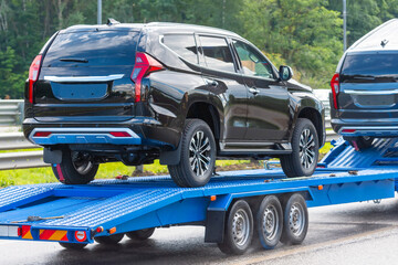 Cars carrier trailer with new car on highway.