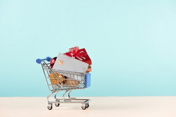 Christmas shopping concept. Shopping cart full with christmas gift boxes and credit card.