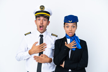 Airplane pilot and mixed race air hostess isolated on white background surprised and shocked while looking right