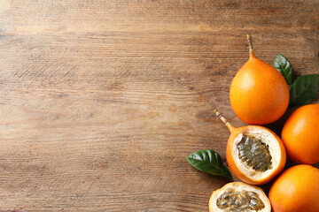 Delicious ripe granadillas on wooden table, flat lay. Space for text