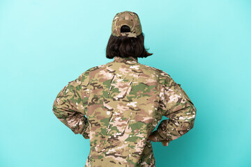 Military mixed race woman isolated on blue background in back position