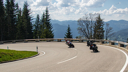 Beautiful alpine summer view with two bikers going fast through a corner at the famous Rossfeld...