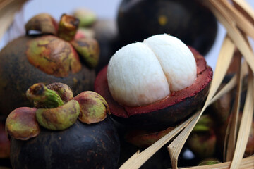 Queen of fruit, Mangosteen in bamboo basket. Cross section of mangosteen showing the deep purple skin and white pulp with delectable sweet and sour taste.
