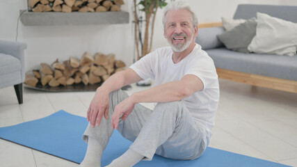 Old Woman Smiling at the Camera while sitting on Excercise Mat