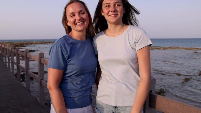 Mother and daughter standing by the sea and showing heart