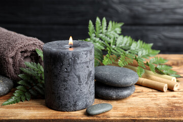 Composition with burning candle and spa stones on wooden table