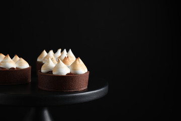Fototapeta na wymiar Delicious salted caramel chocolate tarts on stand against dark background, closeup. Space for text