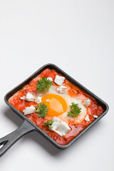 Fried eggs with tomatoes and cheese in a frying pan. Shakshuka, a Jewish dish.
