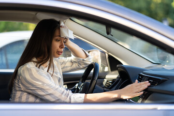 Exhausted young woman suffering from heat inside car with broken air conditioner. Female driver...