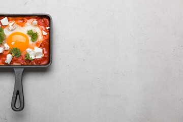 Fried eggs with tomatoes and cheese in a frying pan. Shakshuka, a Jewish dish.
