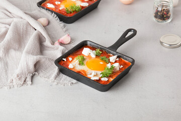 Fried eggs with tomatoes and cheese in a frying pan. Shakshuka, a Jewish dish.
