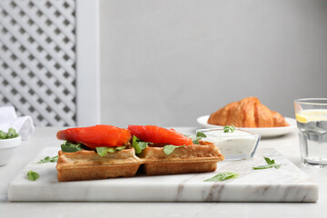 Fresh Belgian waffle with salmon and arugula on white table