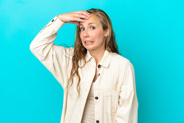 Young caucasian woman isolated on blue background doing surprise gesture while looking to the side
