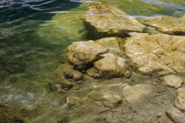 Abstract nature background with transparent water and big granite stones on bottom.