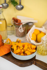 A plate with raw pumpkin pieces on kitchen table. Positive yellow backgorund. Autumn concept. Thanksgiving day