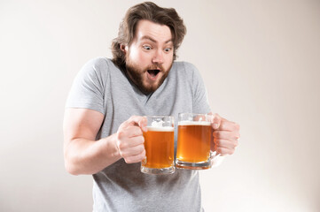 Portrait of a happy young bearded man holding two beer mugs isolated over light gray background