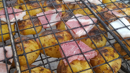 Grilled potatoes with bacon, whole baked on the barbecue grill. Selective focus. Whole small potatoes with bacon bits and grilled. Baked potatoes with grilled bacon.