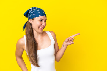 Young English woman isolated on yellow background pointing finger to the side and presenting a product