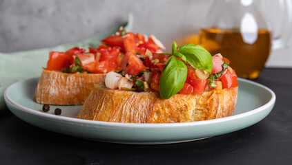 Two slices of tomato bruschetta made from ciabatta bread with diced tomatoes, spices, basil and chopped garlic on a plate, Italian cuisine, selektive focus