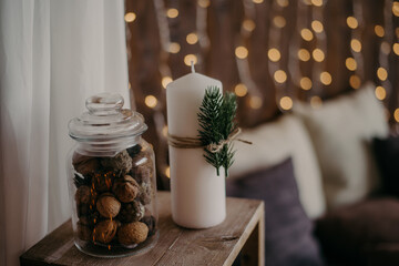 white candles with fir branches and a jar of walnuts