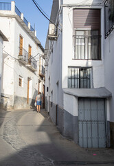 Fototapeta na wymiar Laroles of the Alpujarras street with a small blue door in front and in the background a woman walking