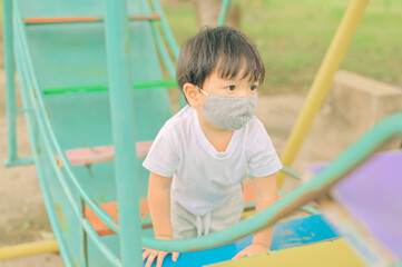 Little boy playing in the playground, the child is wearing a protective mask on the face during the quarantine of coronavirus, covid-19, virus protection.