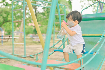 Little boy playing in the playground, the child is wearing a protective mask on the face during the quarantine of coronavirus, covid-19, virus protection.