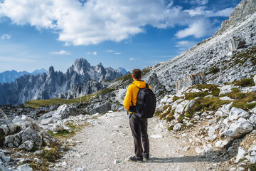 Man in yellow jacket hiking in Tre Cime National park. Cadini di Misurina in the background. Dolomites, Italy, Europe