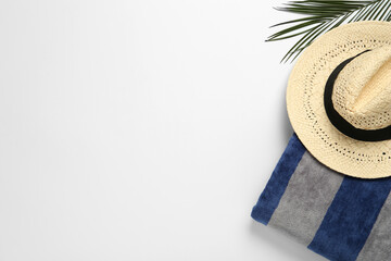 Beach towel and straw hat on white background, top view