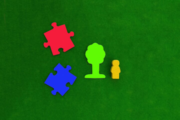 Two pieces of puzzles in blue and red, a tree, a human figure on a green background.