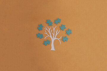 A tree, a crown of blue puzzles on a light brown background. Joint work, project. The result of the interaction.