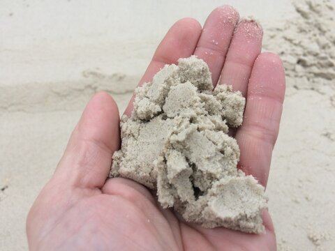 Un homme tenant du sable dans sa main afin d'en v&eacute;rifier la qualit&eacute;