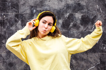 Young woman listening to music. Yellow outfit. She is making silly faces