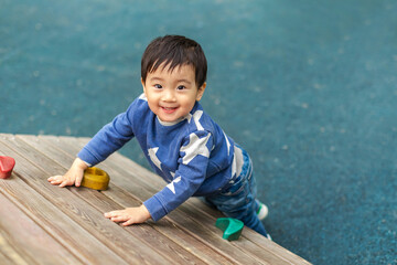 Naklejka premium Asian boy is playing in playground with happy face in summer. Copy space for text