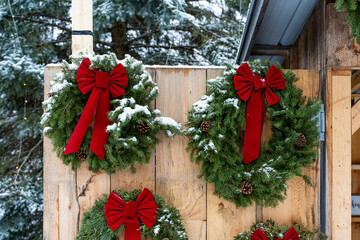 Closeup shot of Christmas wreaths with red ribbons on a wooden wall
