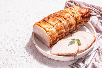 Baked pork loin on a ceramic stand with cutlery