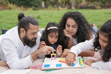 Indian parents having playful time with children at city park - Hindu people enjoy day outdoor - Concept of family love