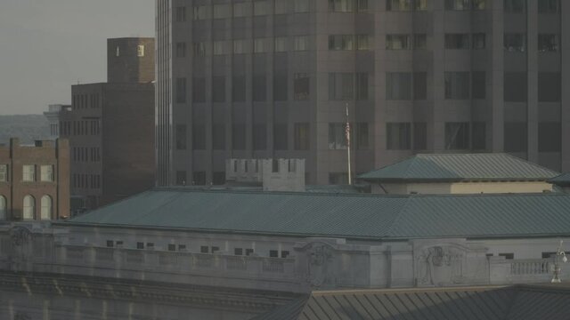 An urban view of downtown rooftops, with an American flag flapping in the wind above federal building. a 4K (S-Log) video clip, Cleveland, OH, United States.