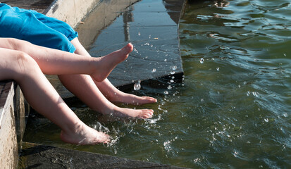 Childrens feet splash in the water of the fountain. High quality photo