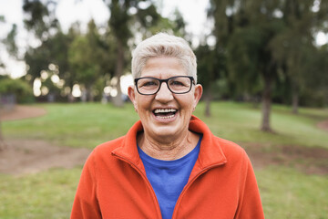 Senior caucasian woman smiling on camera outdoor at city park